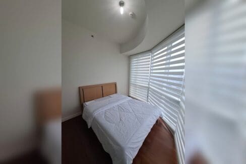 Bedroom with a timber headboard and curved bay window in a Marco Polo condo for rent.