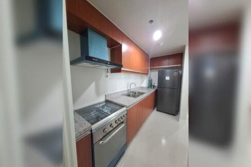 Timber kitchen with granite counters, a gas range with oven and a stainless range hood.