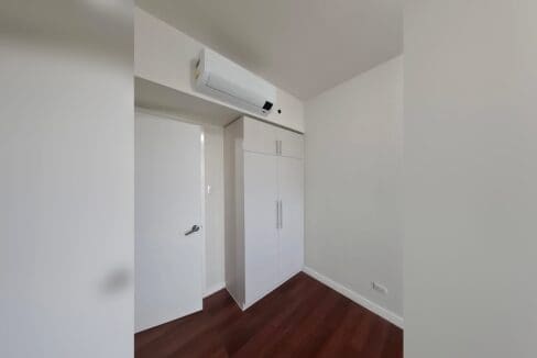 Bedroom with dark hardwood flooring, a built-in wardrobe and split-type air conditioning.