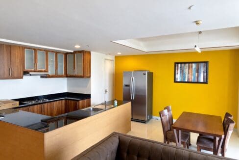Walnut kitchen with frosted-glass upper cabinets and black granite counters opening to the dining area