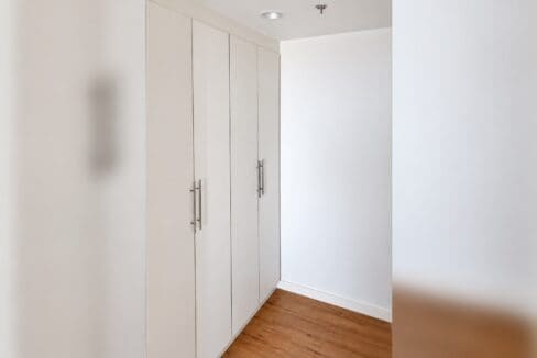 Bank of white built-in wardrobes set along a wood-plank floor