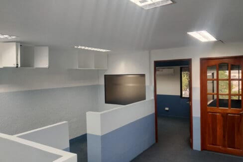 Staff area with a wall-mounted screen and the doorway to the manager offices