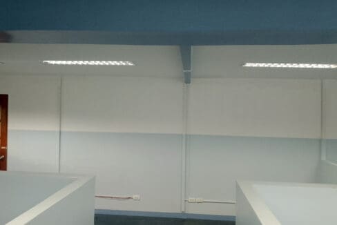 Painted beams and recessed fluorescent lighting over the cubicle area