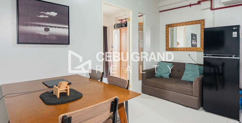 Furnished 1BR condo for rent at Royal Oceancrest Mactan, with a four-seater dining table, tufted sofa and refrigerator