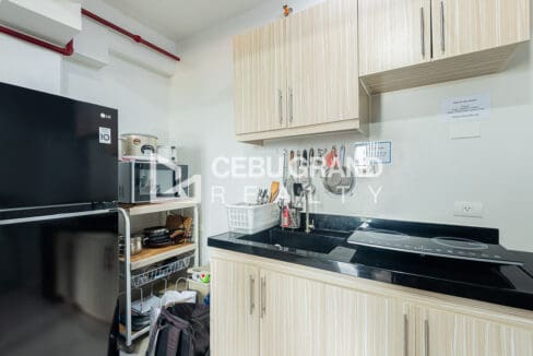 Kitchen with a refrigerator, microwave and rice cooker on an open rack beside the sink