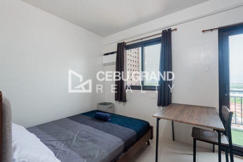 Bedroom at the Royal Oceancrest unit, with a double bed, window-type air conditioning and a study desk