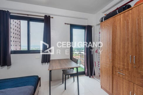 Bedroom windows and glass balcony door looking out over Lapu-Lapu City, with a full-height wardrobe