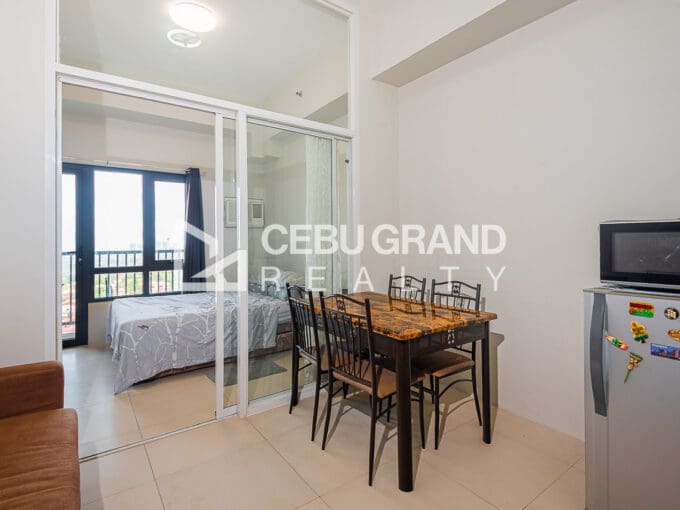 Furnished studio at Sundance Residences with a dining table for four and the glass-enclosed sleeping area behind