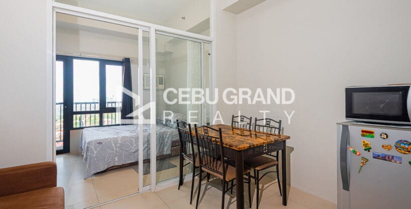 Furnished studio at Sundance Residences with a dining table for four and the glass-enclosed sleeping area behind