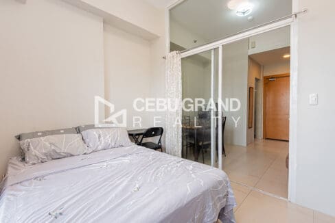 Double bed with the glass partition and sheer curtain looking out to the dining area