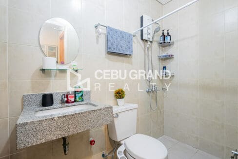 Bathroom with granite vanity, round mirror, water heater and handheld shower