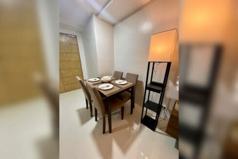 Dining table and chairs beside the living area of a furnished 1-bedroom condo