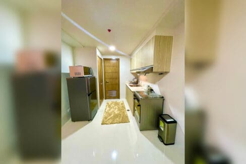 Galley kitchen with refrigerator in a furnished 1-bedroom condo at Taft East Gate
