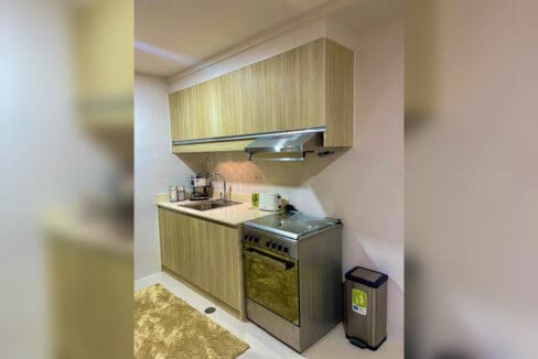 Kitchen counter with cooking range and cabinets in a 1-bedroom condo unit