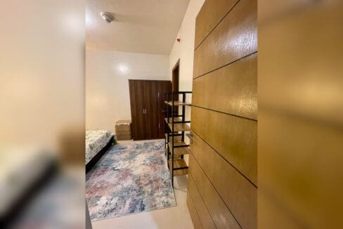 Bedroom doorway with wardrobe and shelving in a furnished 1BR condo