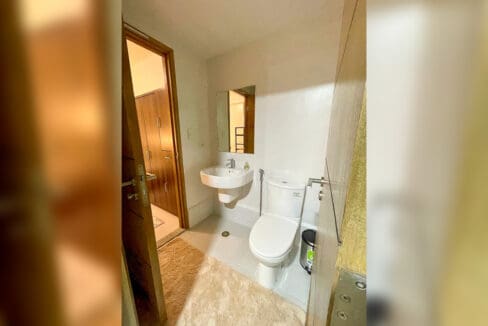 Bathroom with basin and toilet in a furnished 1BR condo unit
