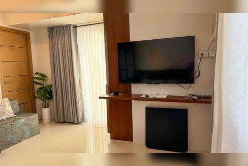 Living area with fabric sofa, TV and window-type air conditioning in a studio unit