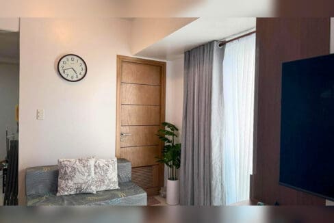Fabric sofa with throw pillows and wall clock near the entry door of a Taft East Gate studio