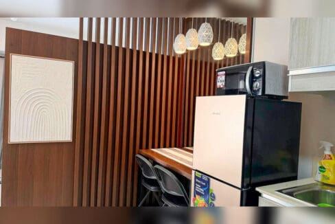 Slatted timber divider with pendant lights, refrigerator and microwave in a studio kitchen