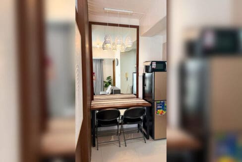 Dining counter for two with folding chairs and full-height mirror in a furnished studio