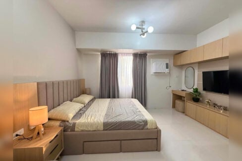 Bed with storage drawers beside the TV wall and window-type air conditioning