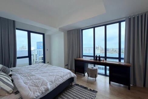 Master bedroom with floor-to-ceiling windows, city and sea views, and a long desk in the 2BR condo for rent at 38 Park Avenue
