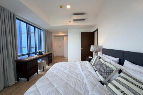 Master bedroom with split-type air conditioning, built-in wardrobe, and grey curtains in the 2BR condo for rent at 38 Park Avenue