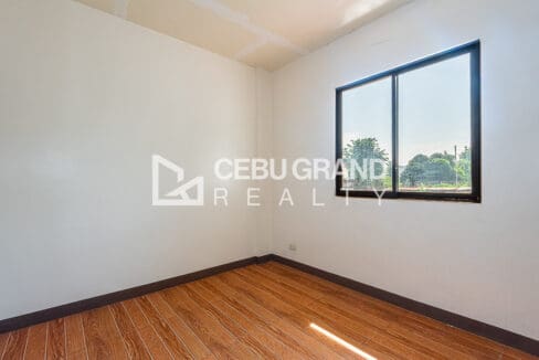 Bedroom corner at the Consolacion townhouse, with a window framing the trees beyond