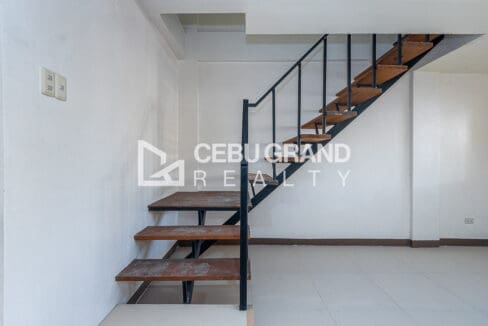 Open-riser timber stair with a black steel balustrade rising from the living area