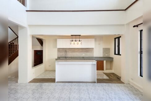 Kitchen with granite-topped island, white cabinets and tile backsplash