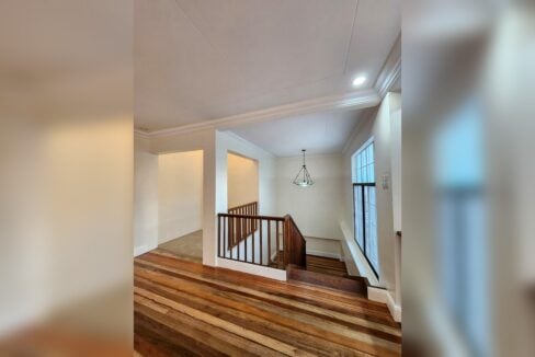 Upstairs landing with hardwood floors and wooden railing