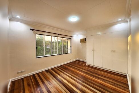 Bedroom with white built-in wardrobe, window-type air conditioning and garden view