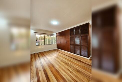 Bedroom with wooden louvered built-in wardrobes and hardwood floors