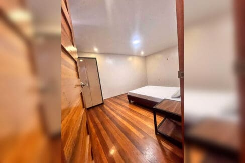 Bedroom with bed, side table and wardrobe on hardwood flooring