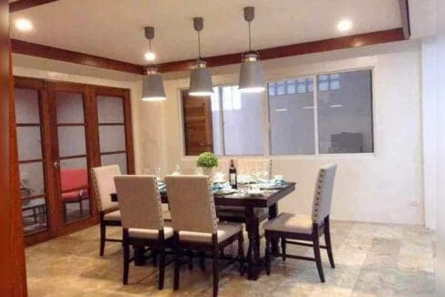 Dining area with upholstered chairs, pendant lights and timber ceiling trim