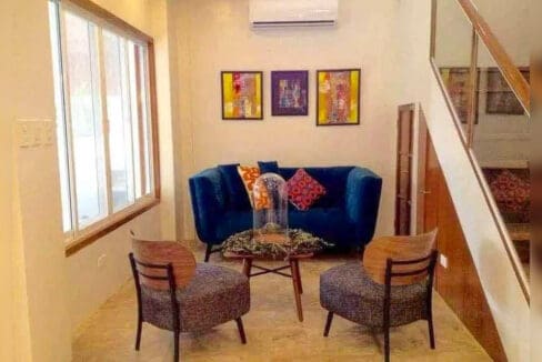 Sitting area with a velvet loveseat, two accent chairs and split-type air conditioning beside the staircase
