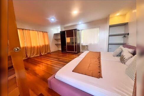 Master bedroom with hardwood floor, wardrobe, open shelving and window-type air conditioning