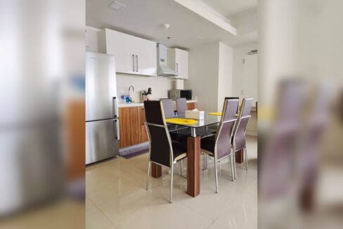 Kitchen with white gloss cabinets, range hood, stainless refrigerator and glass-top dining table