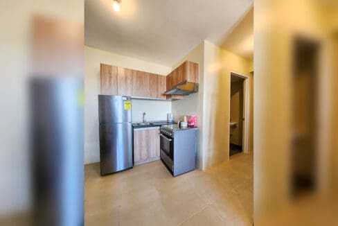 Kitchen with wood-grain cabinets, stainless refrigerator, range and range hood