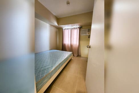 Bedroom with a bed, curtains and window-type air conditioning
