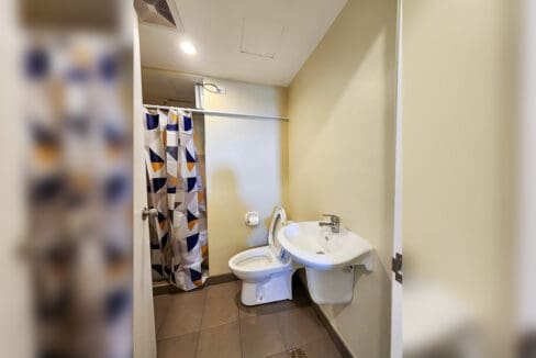 Bathroom with wall-hung basin, toilet and curtained shower