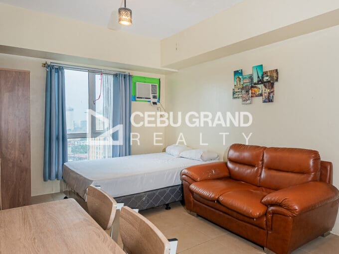 Furnished studio with city view for sale at Avida Riala Tower 3, with the bed by the window and a leather sofa beside it