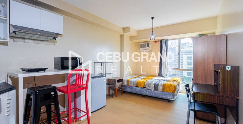 Furnished studio for sale at Avida Tower 2 with the kitchen counter, bar stools and the bed by the window