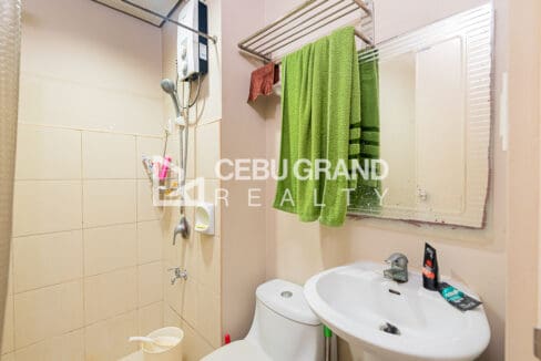 Bathroom with a tiled shower area, water heater, towel rack and mirror above the basin