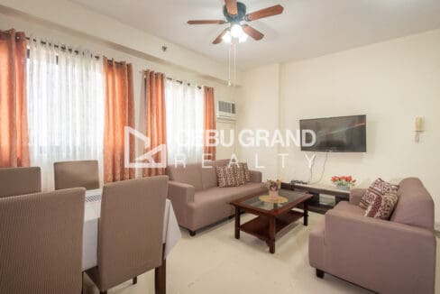 Living area with a wall-mounted television, media console and two sofas beside the dining chairs
