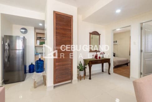 Entry hall with the refrigerator, the kitchen behind it and a tall louvered storage cabinet