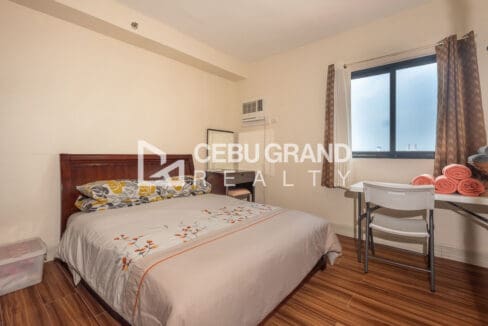 Master bedroom with a timber headboard, window-type air conditioning and a desk by the city-facing window