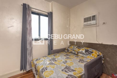 Second bedroom at the Kasambagan condo, with window-type air conditioning and a curtained window