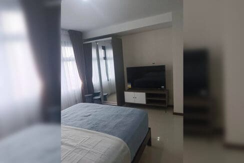 Mirrored sliding wardrobe and flatscreen TV on a media console in the furnished studio at Galleria Residences