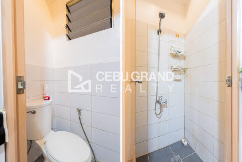 Bathroom with a tiled shower area and handheld shower, and a separate toilet with a bidet spray